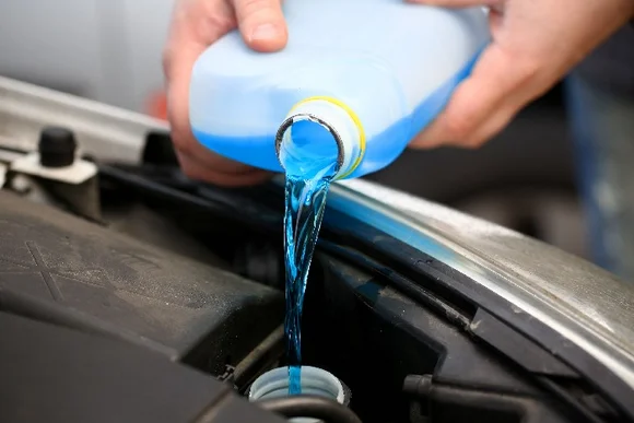 Blaue Flüssigkeit wird in Auto gegossen